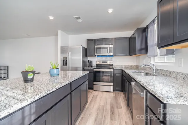 a kitchen with stainless steel appliances granite countertop a sink a stove and a wooden cabinets