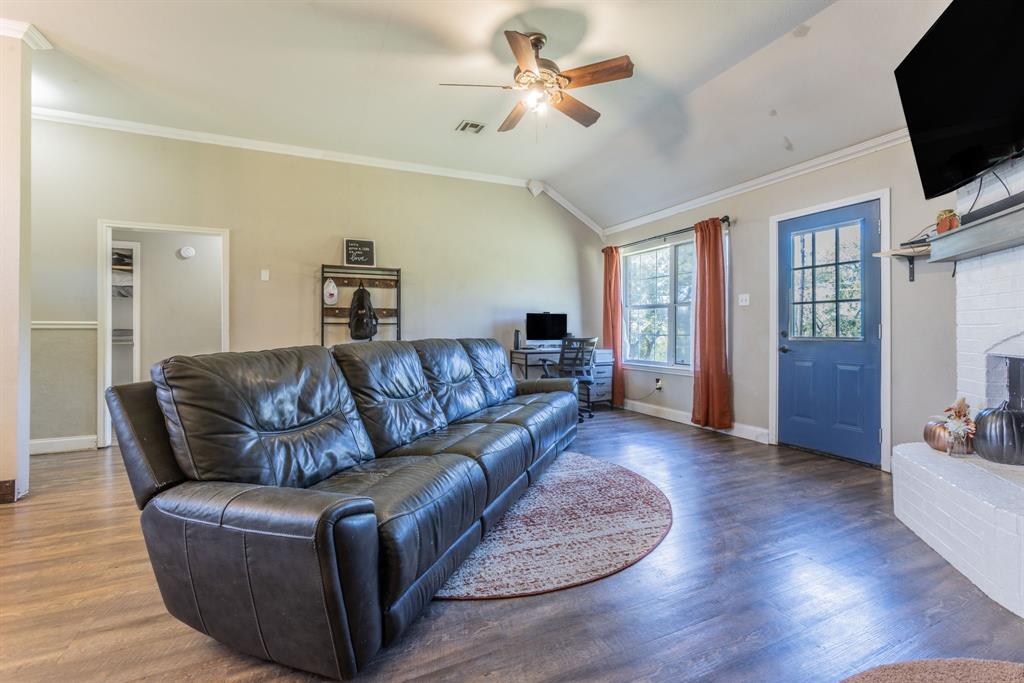 4930 Spring Valley Road Lorena, TX 76655 - Photo 4 of 34 Vaulted ceiling, wood-finish flooring, white brick fireplace, ceiling fan, and a blue paneled door with glass inserts