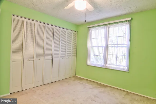 an empty room with a window and a ceiling fan