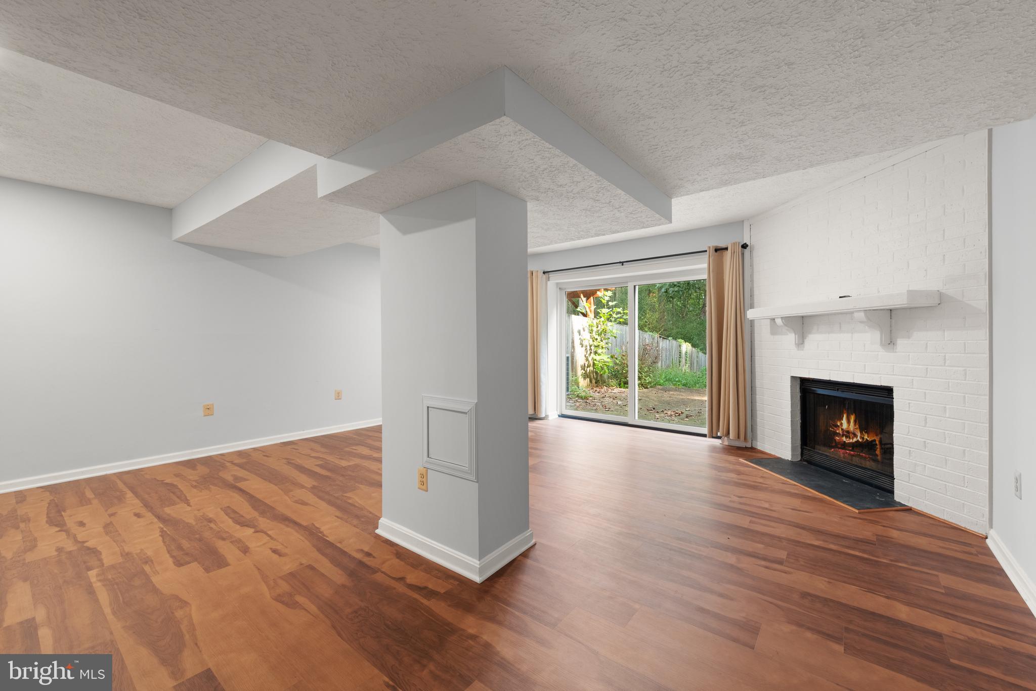 11321 Crescendo Place Silver Spring, MD 20901 - Photo 22 of 24 an empty room with wooden floor fireplace and windows