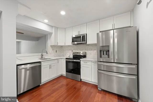 a kitchen with cabinets stainless steel appliances and wooden floor
