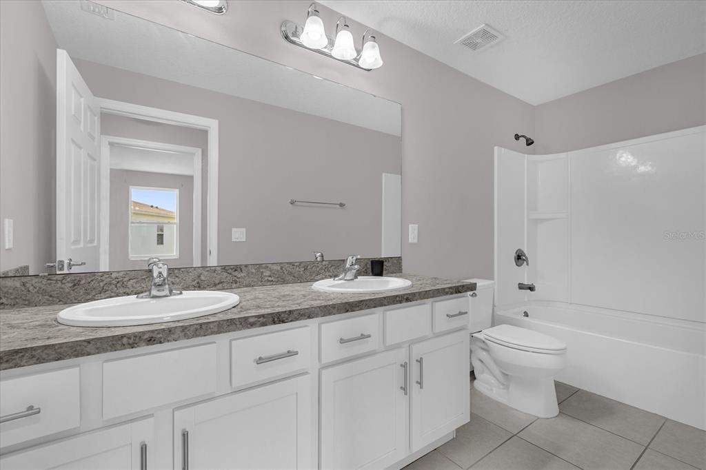 3470 Beau Road Kissimmee, FL 34746 - Photo 26 of 40 a bathroom with a granite countertop double vanity sink a mirror and a toilet