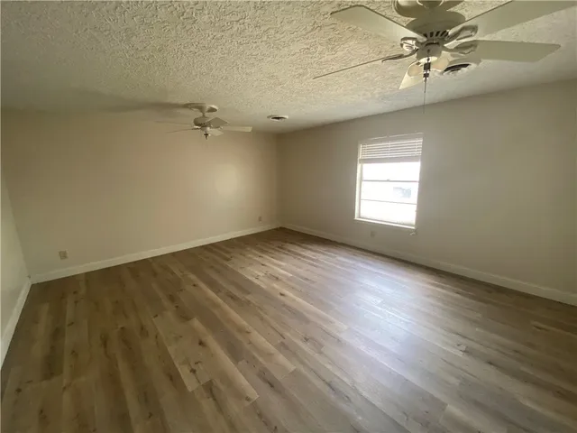 an empty room with a window and ceiling fan