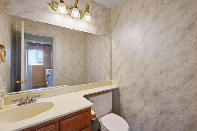 a bathroom with a granite countertop sink and a toilet