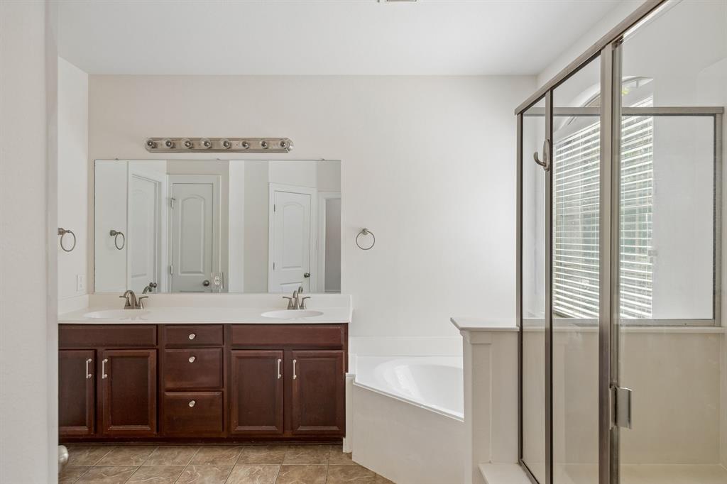 960 Remuda Road Frisco, TX 75033 - Photo 11 of 39 Dual vanity with dark wood-finish cabinetry, built-in soaking tub, and glass-enclosed shower