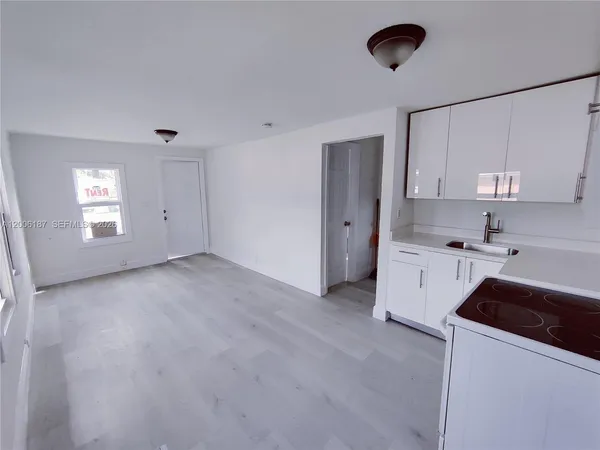 a view of a kitchen with a sink and dishwasher a refrigerator with white cabinets