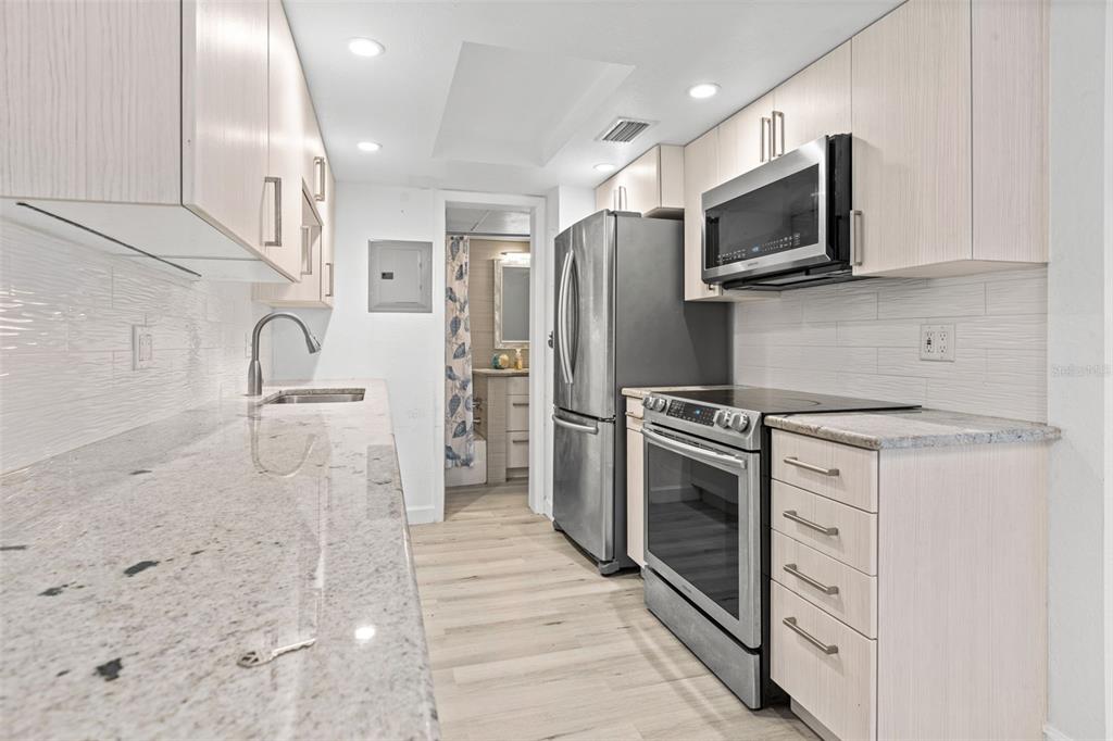 8921 Blind Pass Road, Unit 142 St. Pete Beach, FL 33706 - Photo 14 of 22 a kitchen with granite countertop a refrigerator stove and microwave