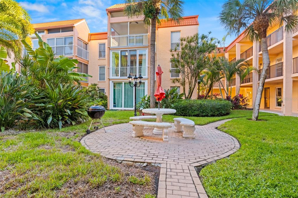 8921 Blind Pass Road, Unit 142 St. Pete Beach, FL 33706 - Photo 22 of 22 a view of a building with a yard and plants