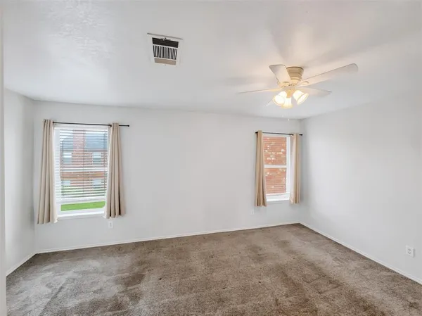an empty room with windows and ceiling fan