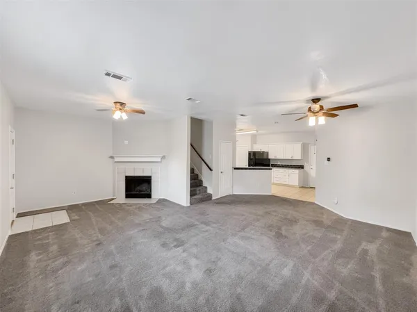 an empty room with fireplace and ceiling fan
