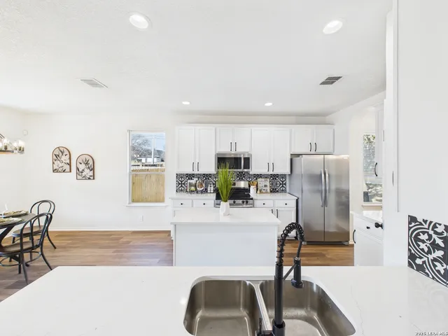 a living room with stainless steel appliances furniture a refrigerator and a kitchen view