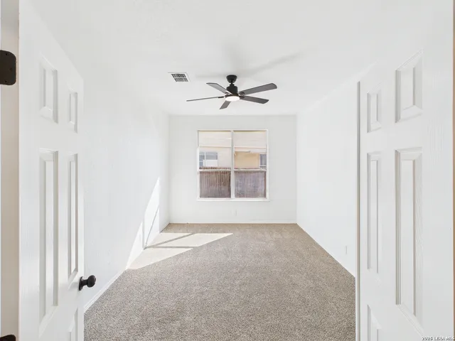 an empty room with windows and a ceiling fan