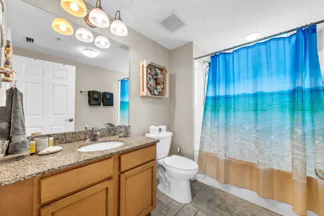 a bathroom with a granite countertop sink a toilet and a mirror