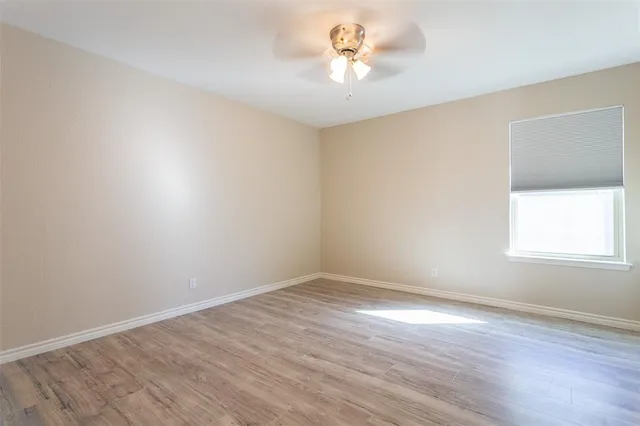 an empty room with a window and a chandelier fan