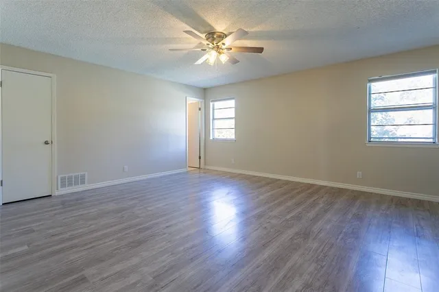 an empty room with wooden floor and windows