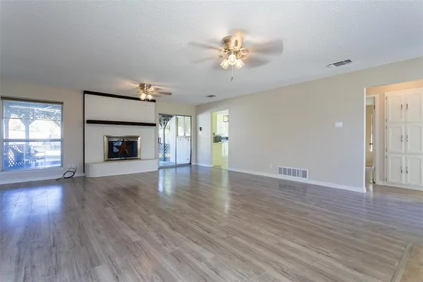 an empty room with wooden floor fireplace and windows