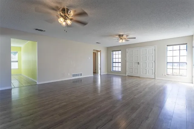 a view of an empty room with window and wooden floor