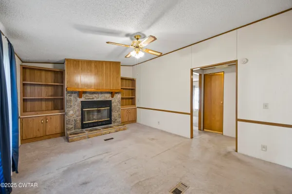 a view of empty room with a fireplace and fan