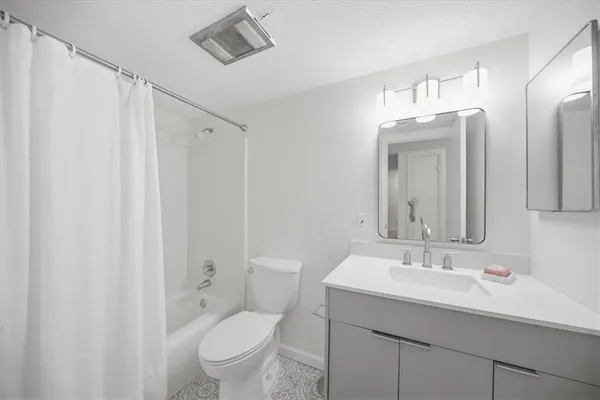 a bathroom with a toilet a sink a mirror a shower and vanity