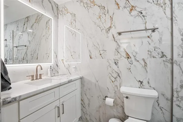 a bathroom with a granite countertop sink a toilet and a mirror