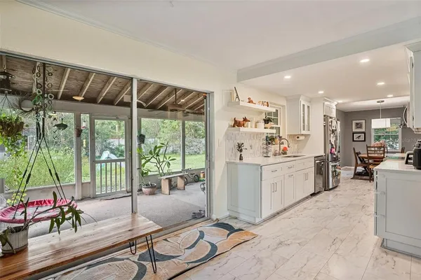 a kitchen with stainless steel appliances kitchen island granite countertop a refrigerator a sink dishwasher a dining table and chairs with the ocean view
