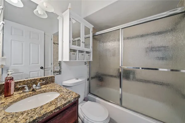 a bathroom with a granite countertop sink toilet and shower