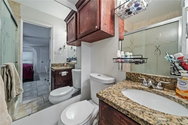 a bathroom with a granite countertop toilet sink and mirror