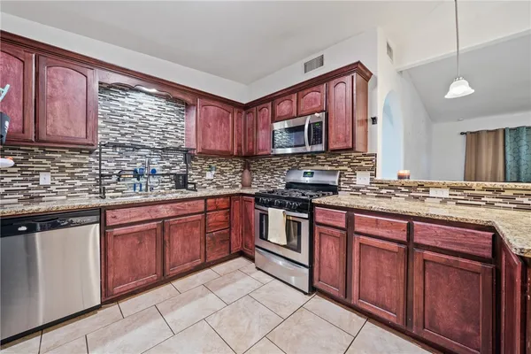 a kitchen with stainless steel appliances granite countertop a sink stove and cabinets