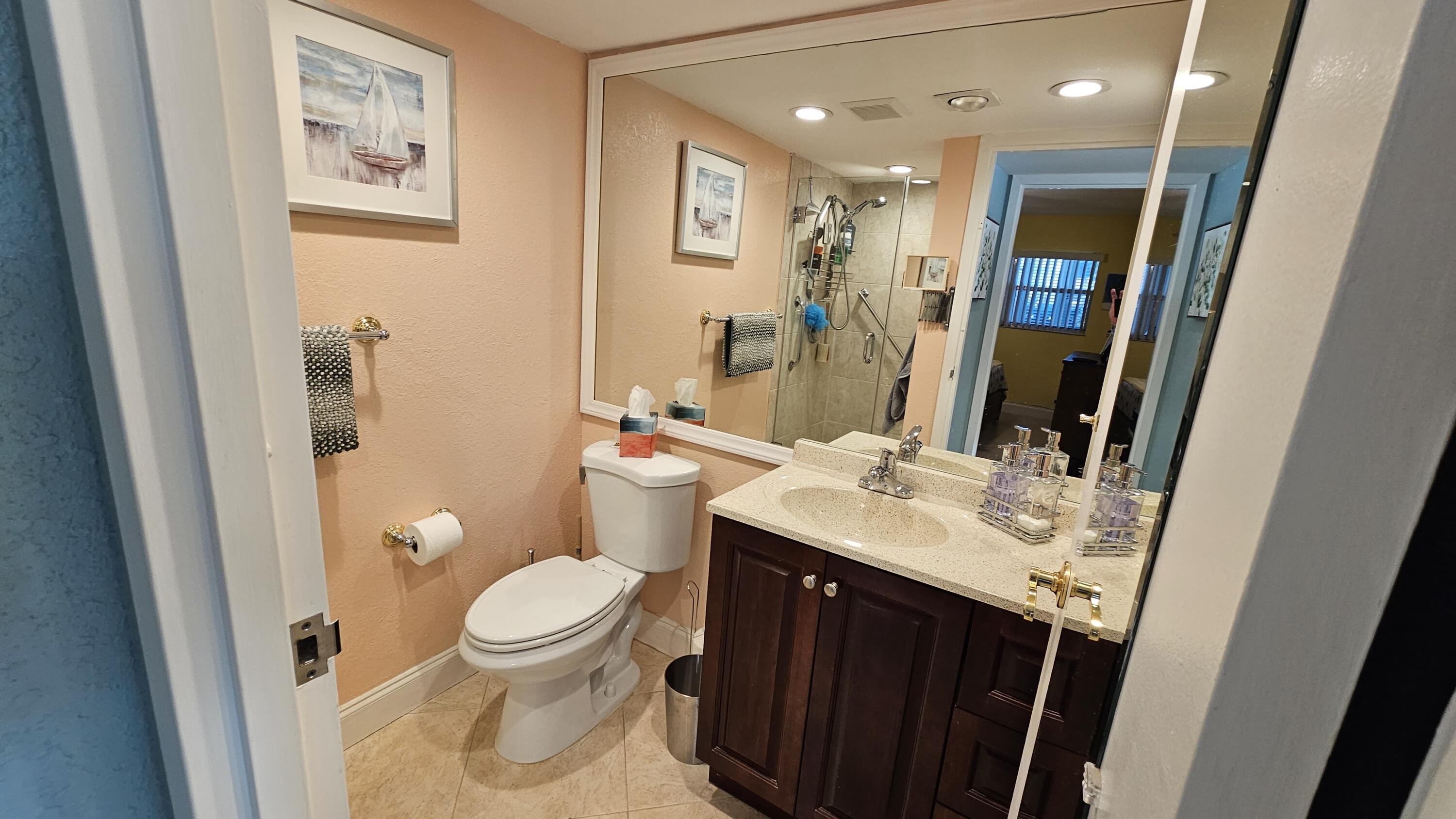 256 Seville K Delray Beach, FL 33446 - Photo 12 of 45 a bathroom with a sink a toilet a mirror a vanity and shower