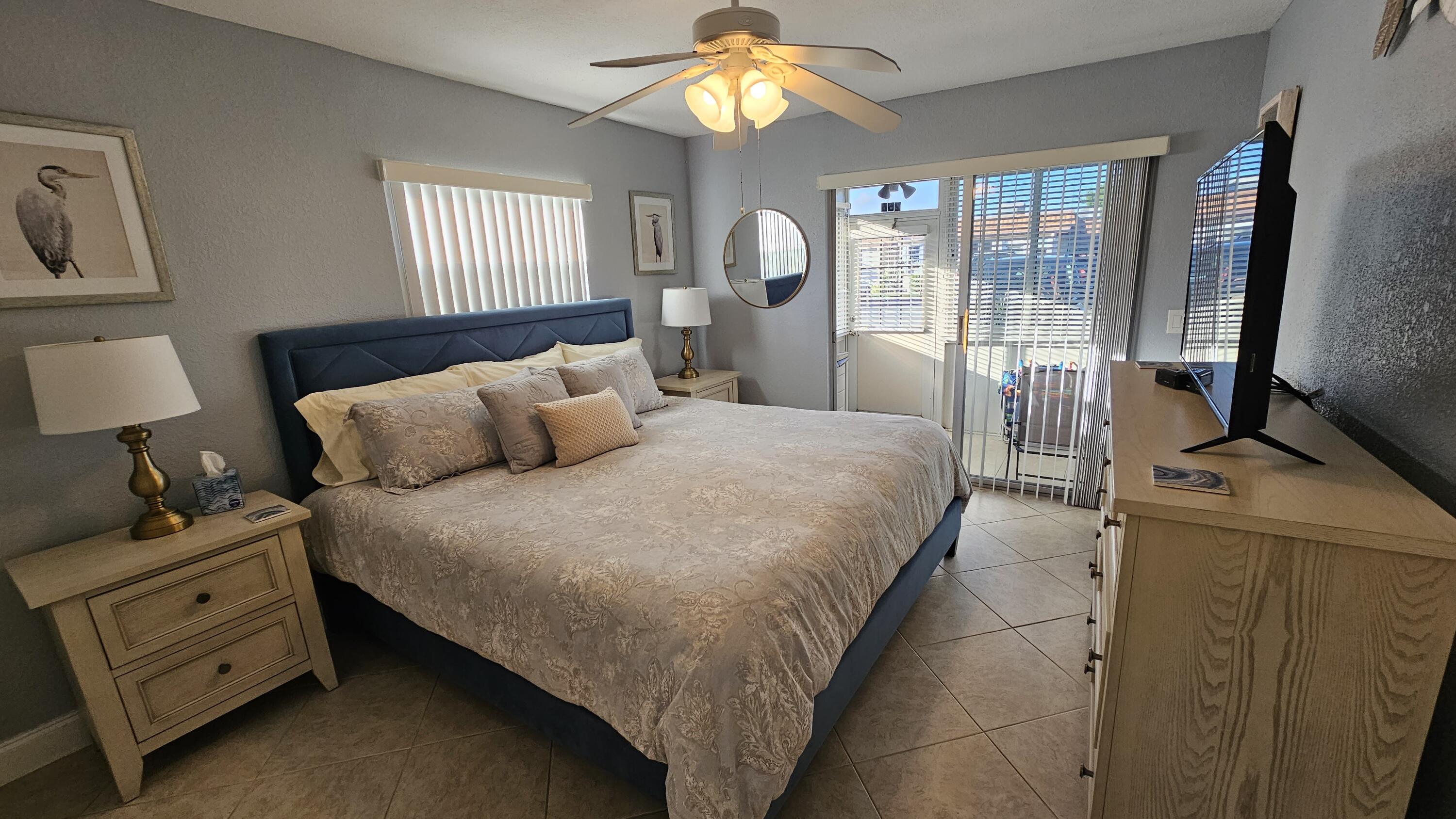 256 Seville K Delray Beach, FL 33446 - Photo 14 of 45 a bedroom with a bed and a flat tv screen on dresser