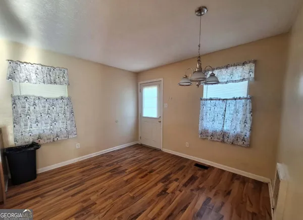 a view of an empty room with window and wooden floor