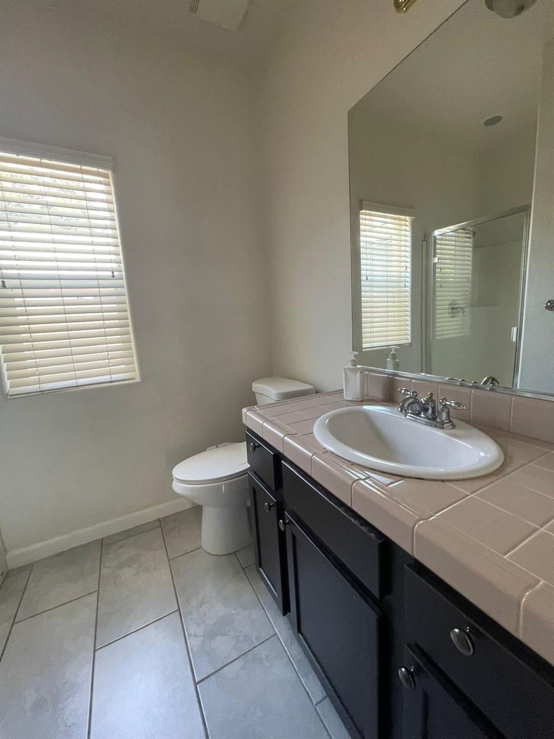 3123 Burgan Avenue Clovis, CA 93611 - Photo 19 of 26 a bathroom with a granite countertop sink a toilet and a mirror
