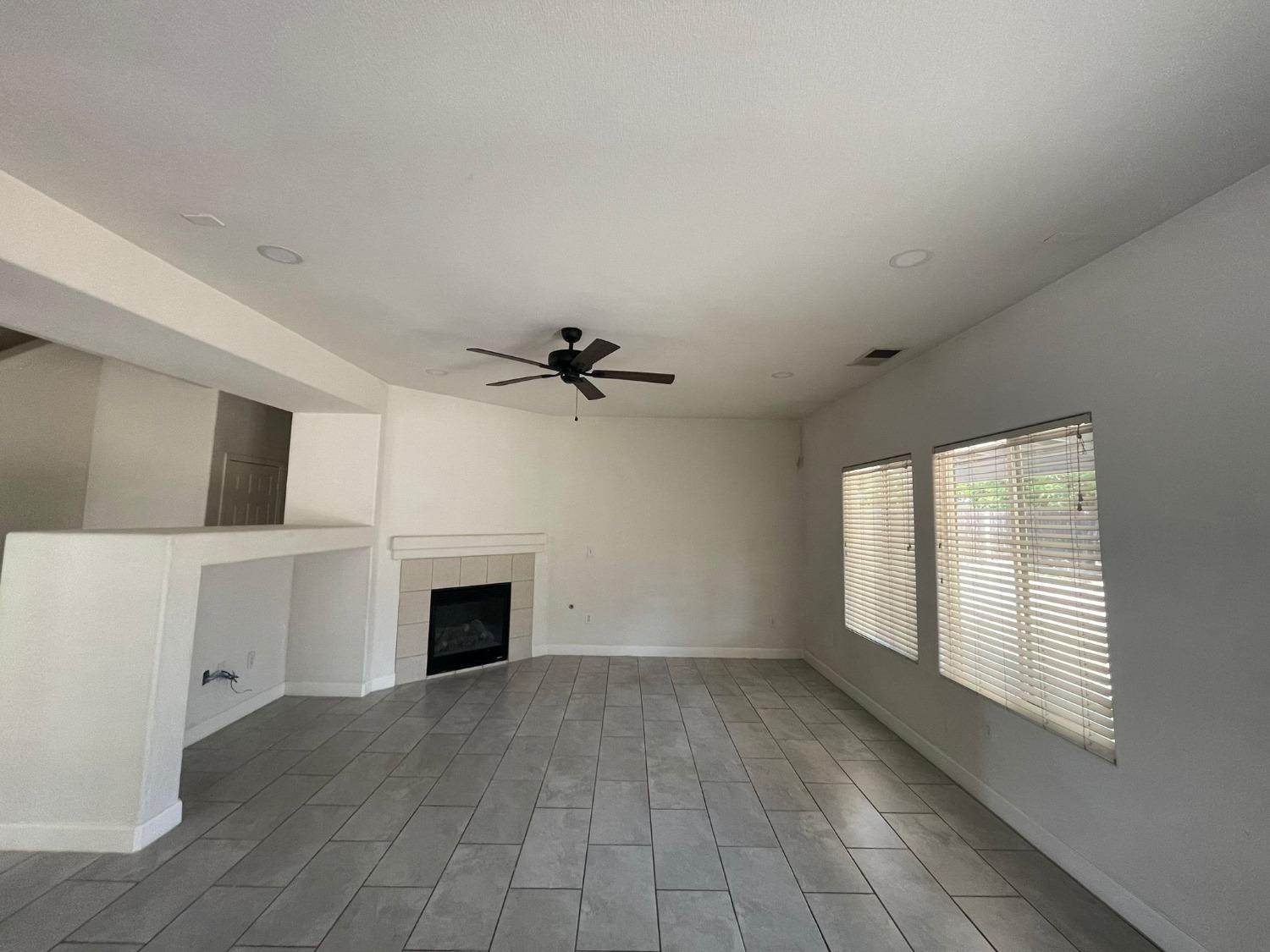 3123 Burgan Avenue Clovis, CA 93611 - Photo 8 of 26 a view of a livingroom with a fireplace a ceiling fan and windows