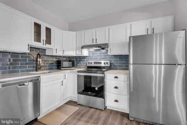 a kitchen with cabinets stainless steel appliances and wooden floor