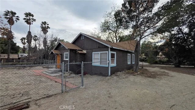 a view of a dry yard with trees in the background