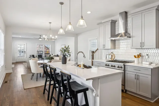 an empty room with wooden floor chandelier fan and windows