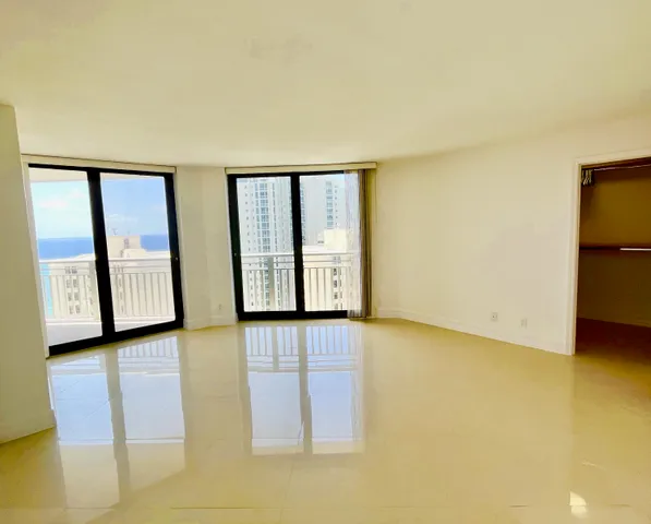 a view of an empty room with window and refrigerator
