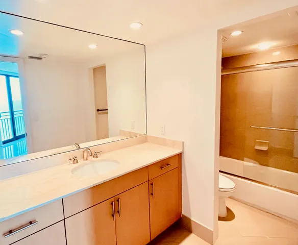 a bathroom with a sink and mirror with bathtub