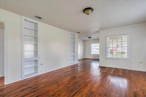an empty room with wooden floor and windows