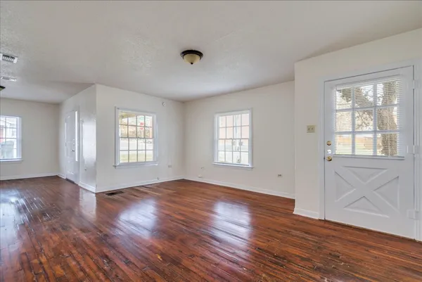 an empty room with wooden floor and windows
