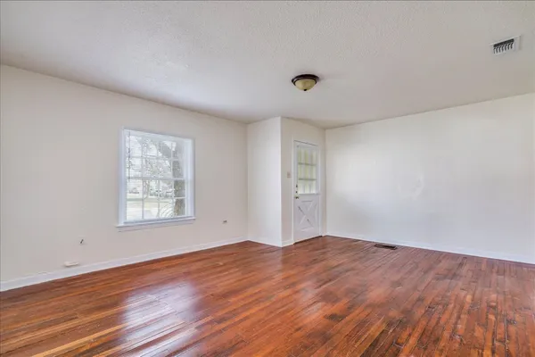 an empty room with wooden floor and windows