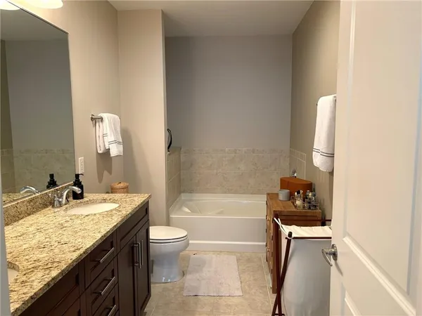 a bathroom with a granite countertop sink a toilet and bathtub