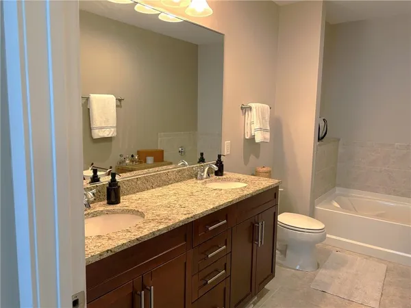 a bathroom with a granite countertop sink a toilet and a large mirror