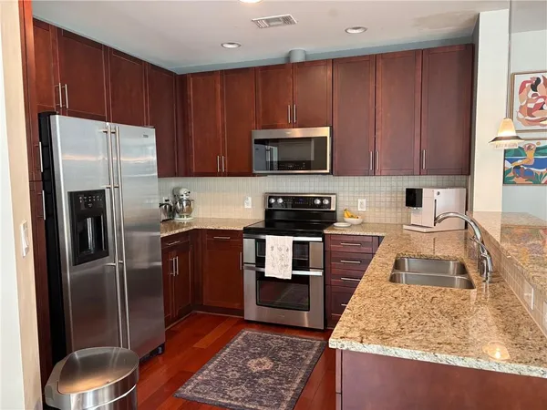 a kitchen with granite countertop wooden cabinets a refrigerator and a sink