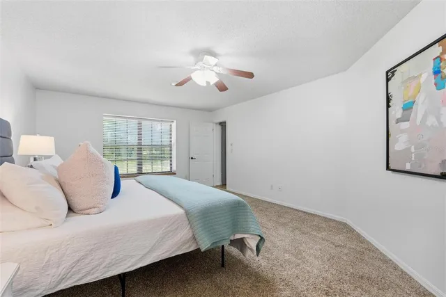 a bedroom with a large bed and a chandelier fan