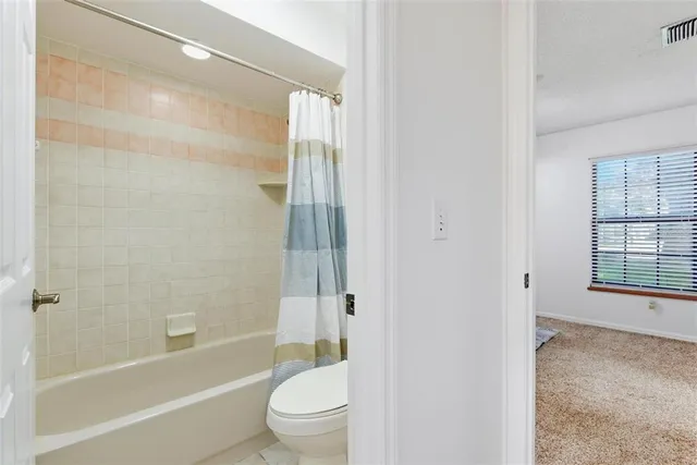 a view of an empty room with furniture and a window