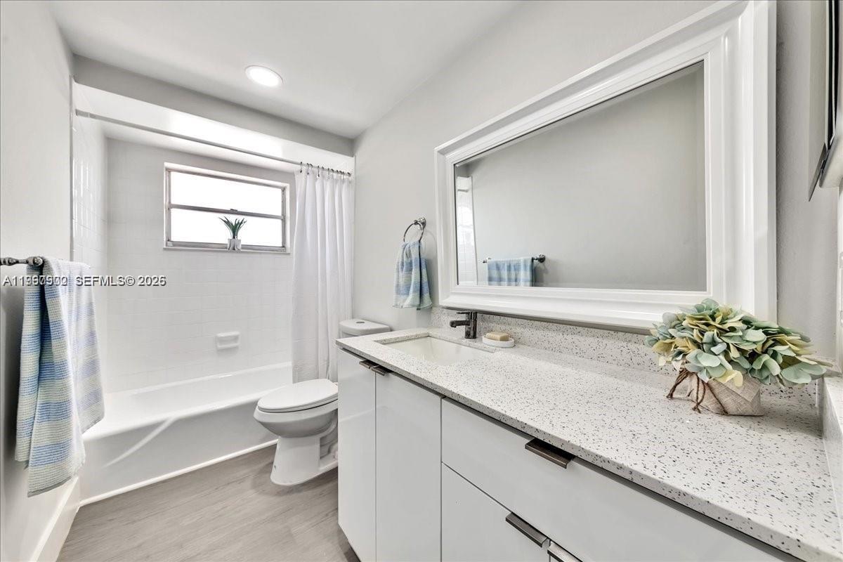 1750 West 46th Street, Unit 433 Hialeah, FL 33012 - Photo 4 of 27 a bathroom with a granite countertop sink a toilet and a mirror