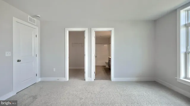 an empty room with a window and a kitchen