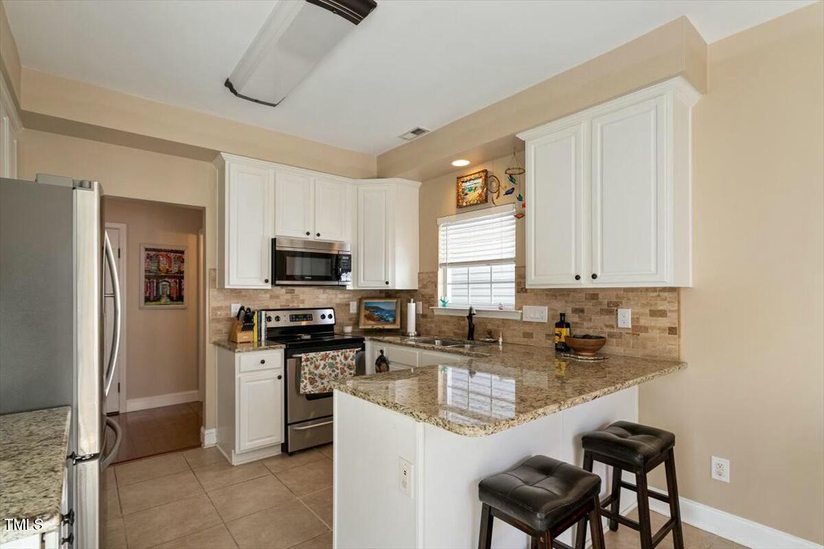 1104 Garnet Ridge Way Raleigh, NC 27607 - Photo 11 of 20 a kitchen with stainless steel appliances granite countertop a sink a stove and a refrigerator
