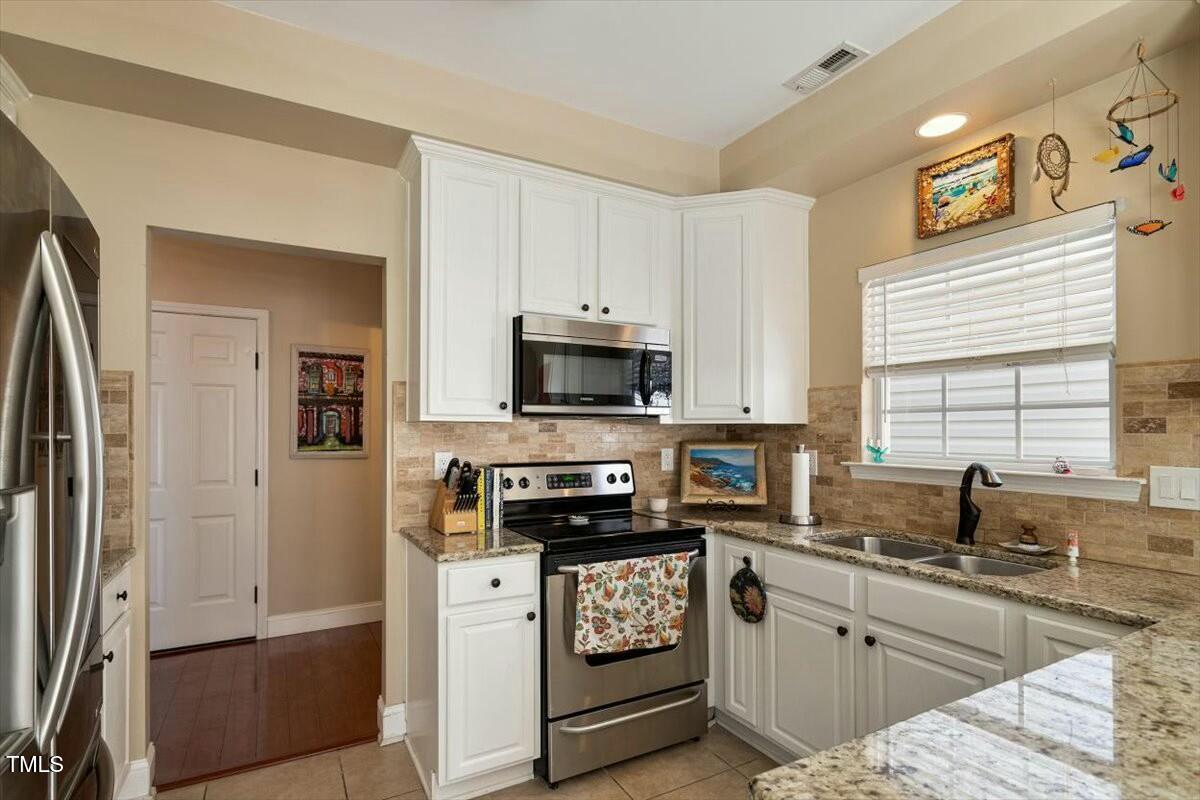 1104 Garnet Ridge Way Raleigh, NC 27607 - Photo 10 of 20 a kitchen with stainless steel appliances white cabinets a sink a stove a refrigerator and a microwave